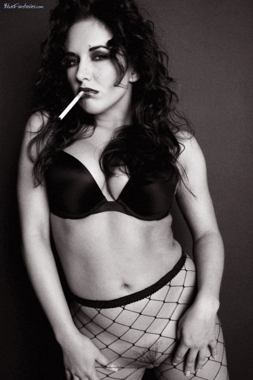 Smoking brunette Zoe Britton in high heels and black fishnet pantyhose fantastically teasing on camera.