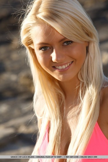 The blonde bimbo Pinky June is on the beach slowly sliding her bright pink bikini down