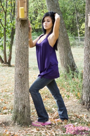 Flirtatious honey Raven Riley with jet black hair gives seductive striptease near the tree.