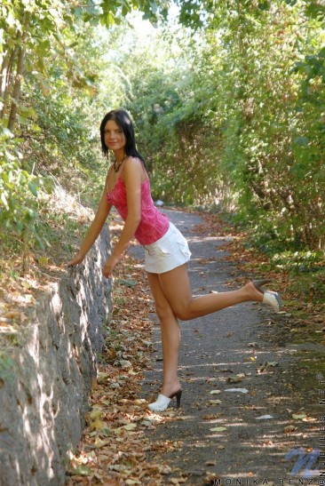 Teeny brunette Monika Benz in white mini-skirt pulls off her black panties in the park